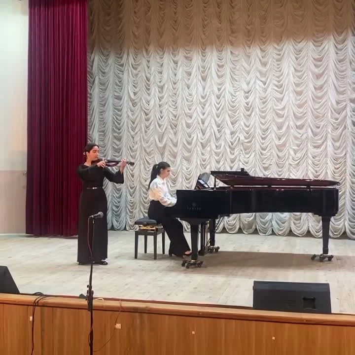 Ева играет на скрипке на фоне белых и красных занавесей